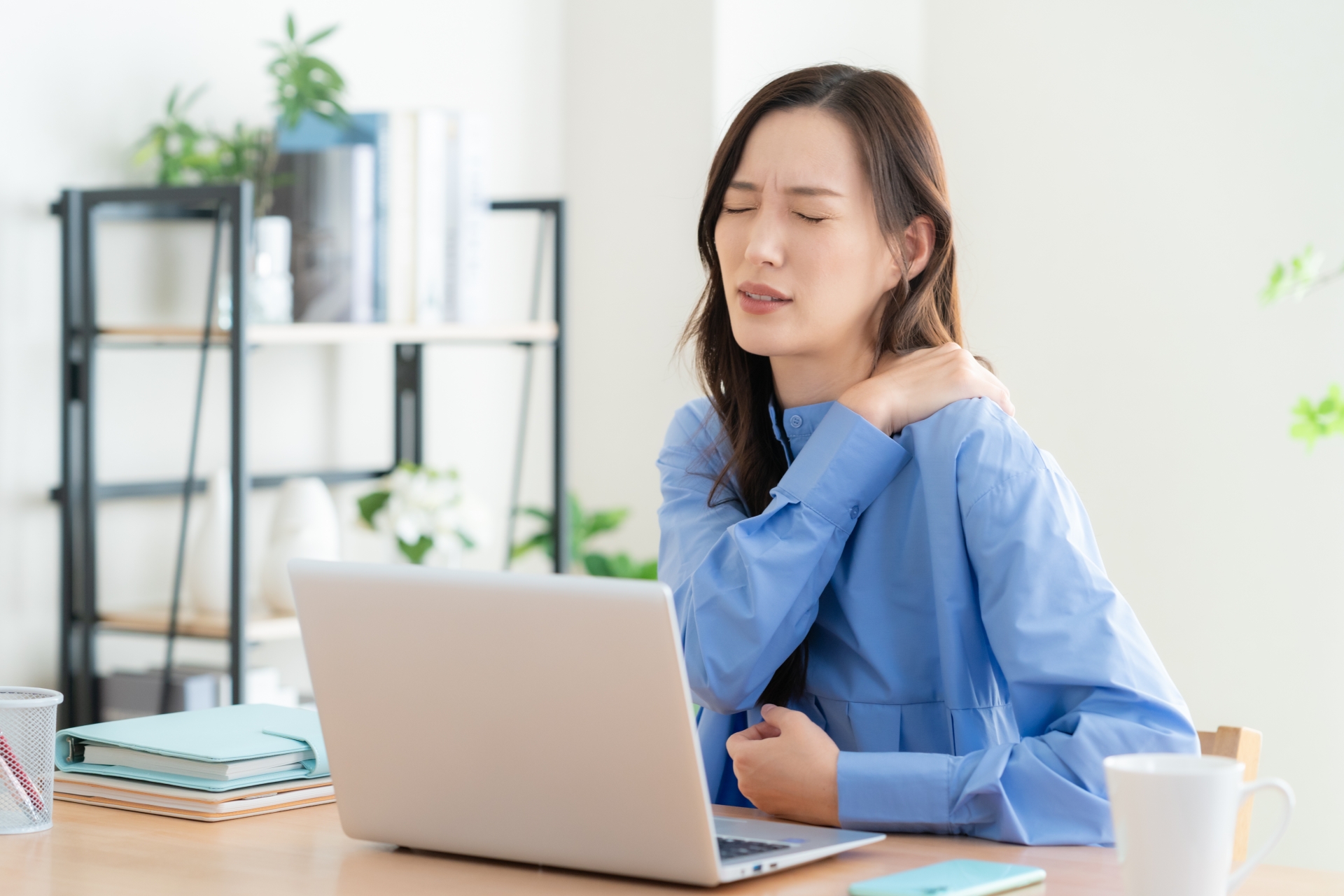 姿勢が悪く肩こりに悩む女性のイメージ