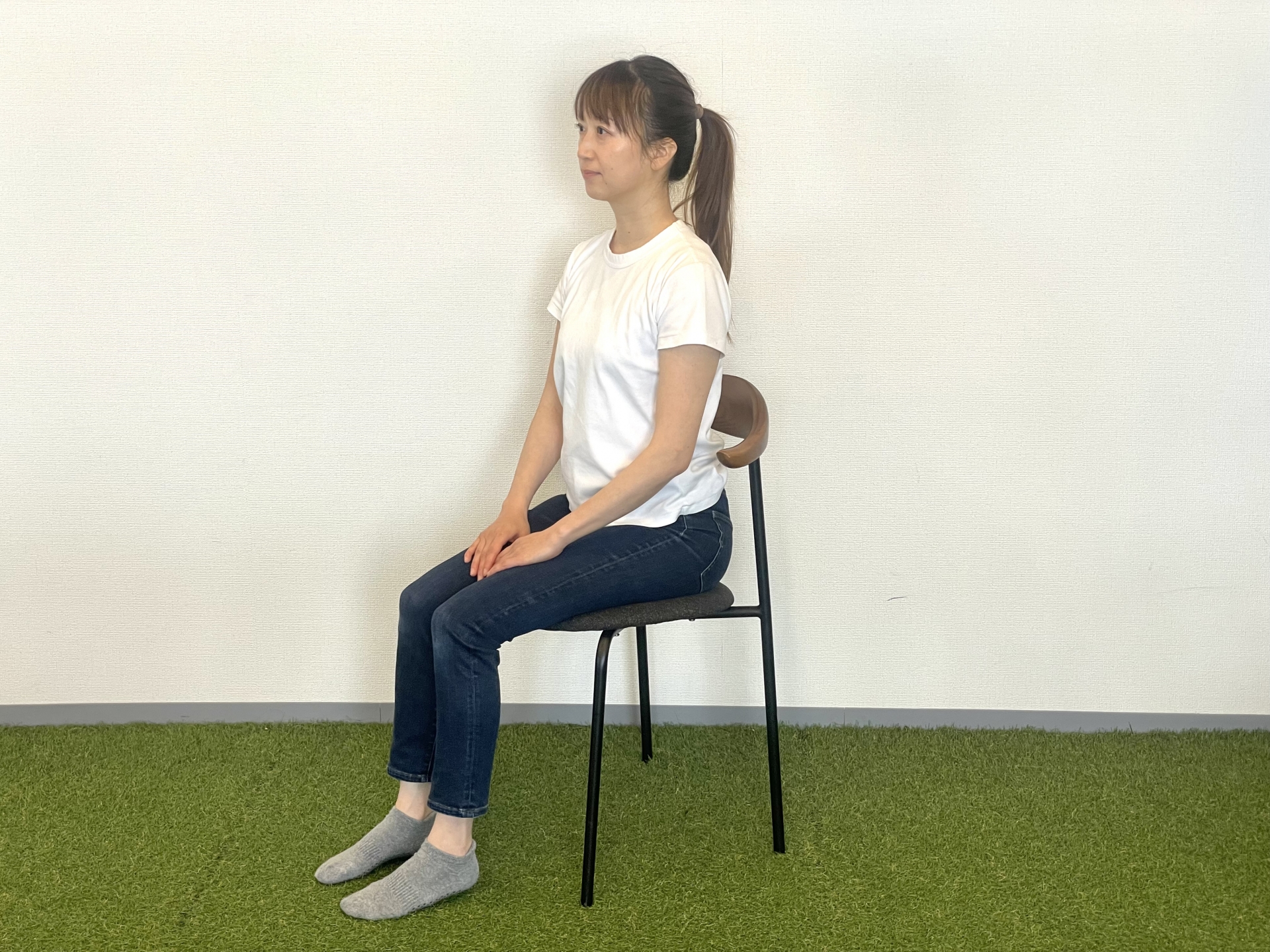 椅子に正しく座り直し、腰をやさしく意識している女性のイメージ